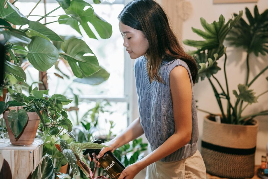 A person watering indoor plants with a small watering can in winter