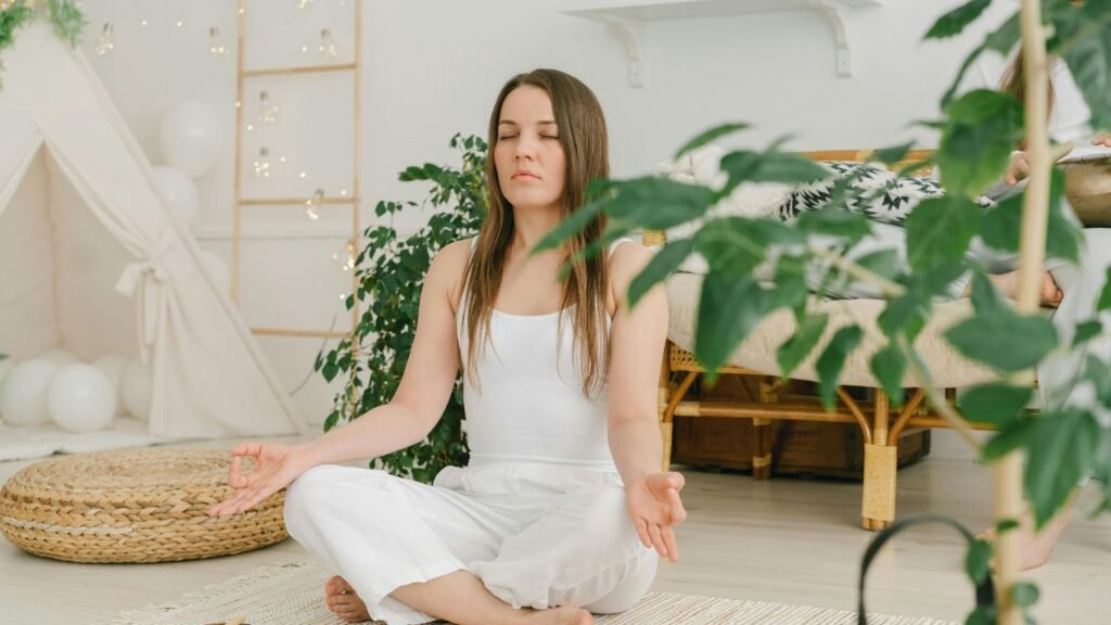 A person meditating beside indoor plants, showcasing the calming effect of greenery